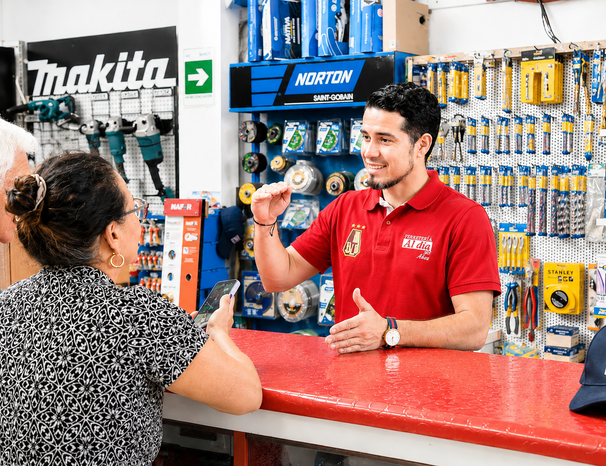 Empleado de Ferretería Al Día gestionando inventario de productos y herramientas eléctricas en sala de ventas